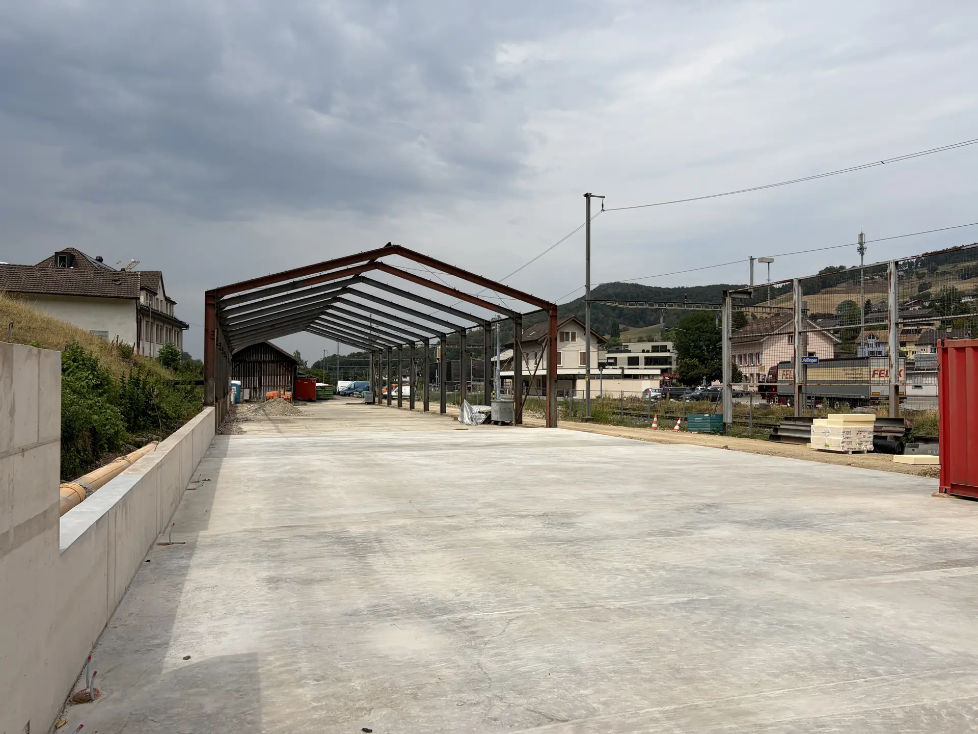 Blick der Länge nach über die neue Bodenplatte durch das Stahlskelett der Halle