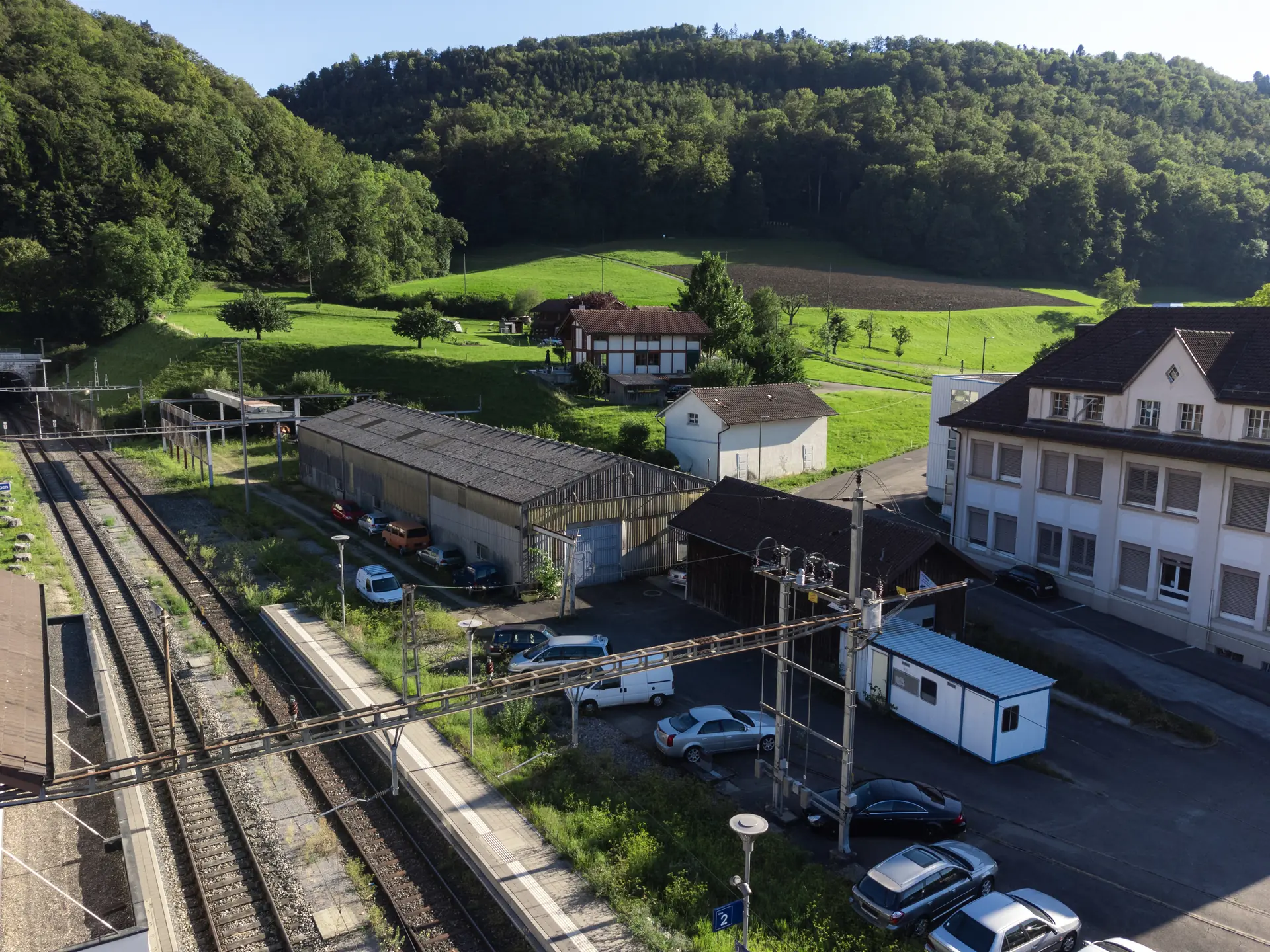Luftbild des Areals vor dem Umbau mit Stahlbiegehalle, hölzernem Güterschopf und den Bahngleisen